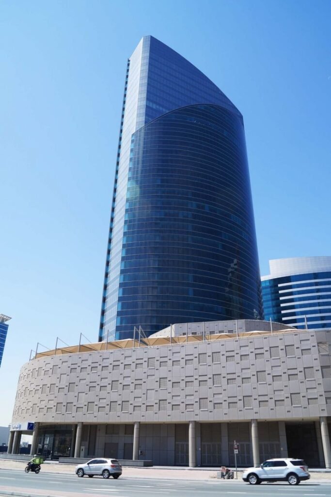 Skyscraper with curved glass facade against clear blue sky.