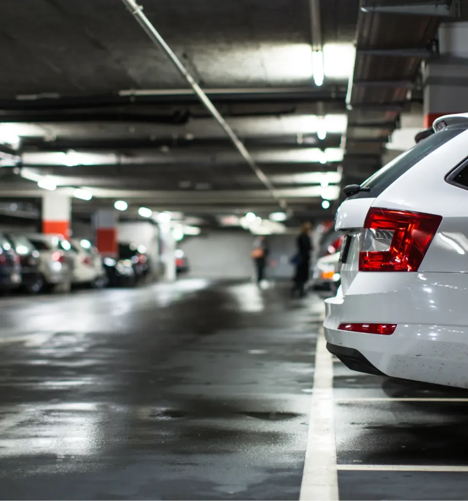 White car parked in a dark, wet underground garage