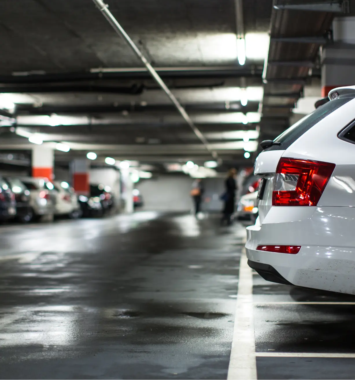White car parked in a dark, wet underground garage