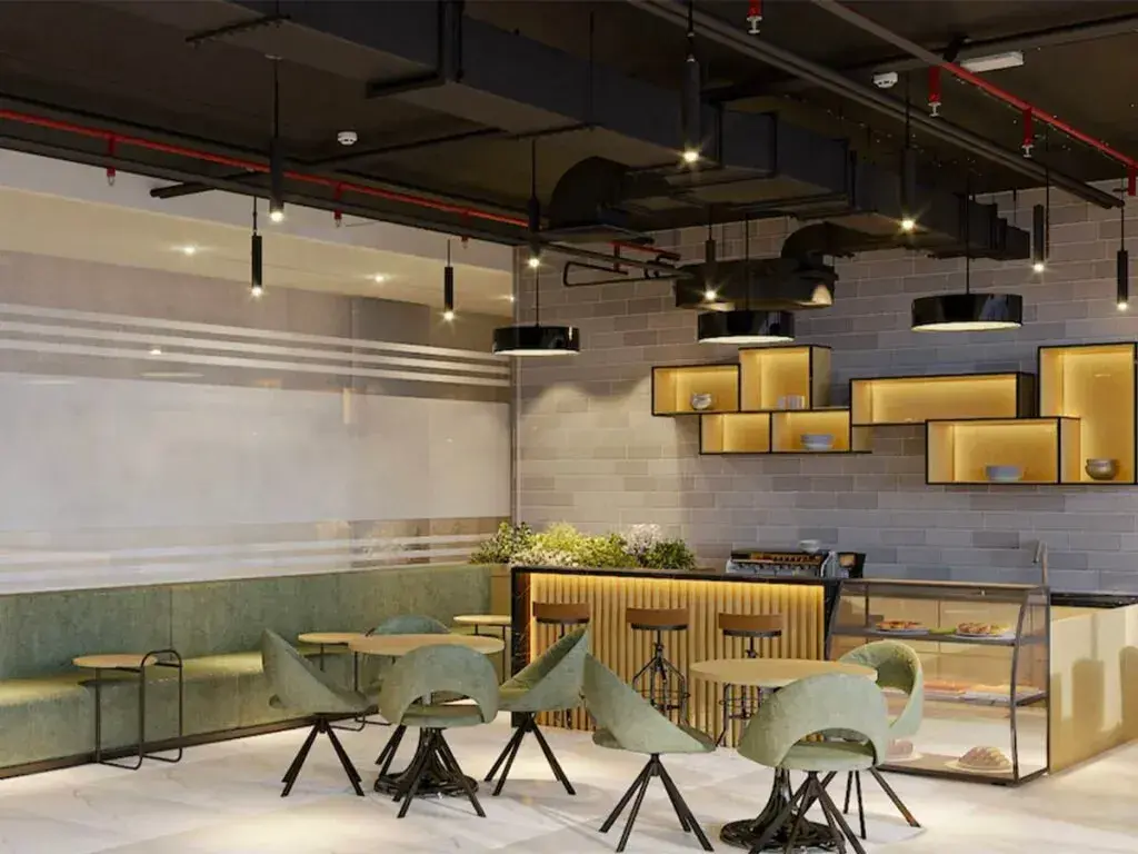 Interior photograph of a modern cafe or lounge with green seating and industrial lighting.