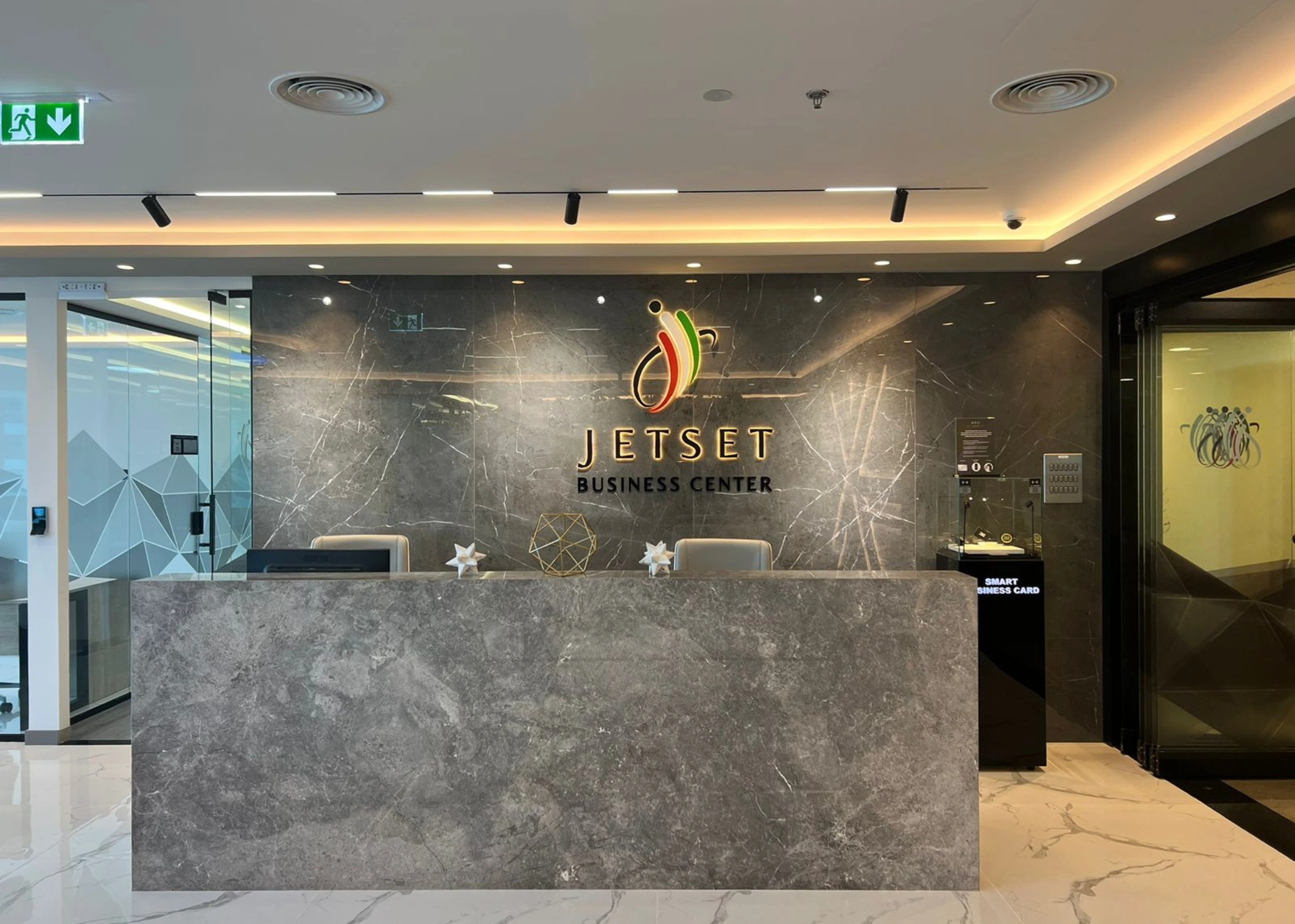 Sleek marble reception desk with illuminated "JETSET BUSINESS CENTER" logo.