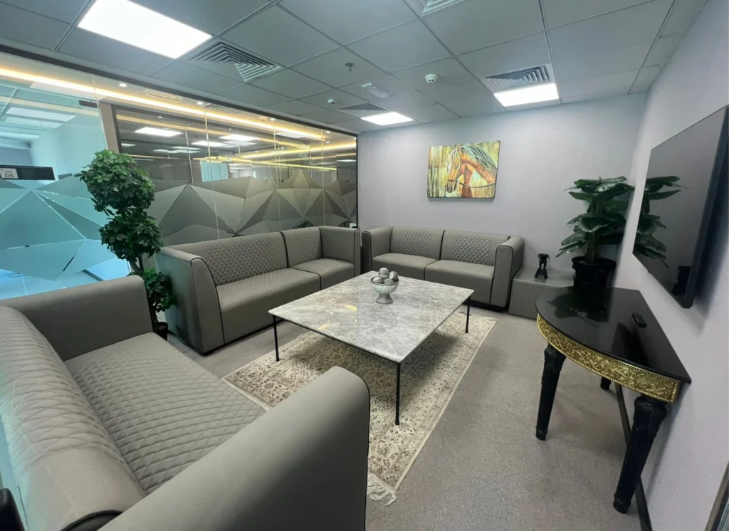 Office waiting area with grey sofas, horse painting, and marble table.