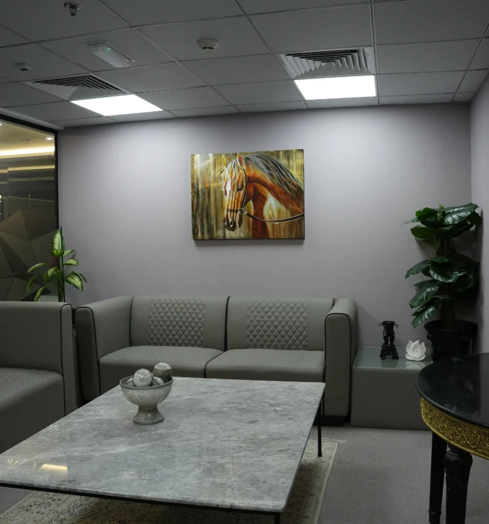 Small professional waiting area with grey sofa and horse painting.