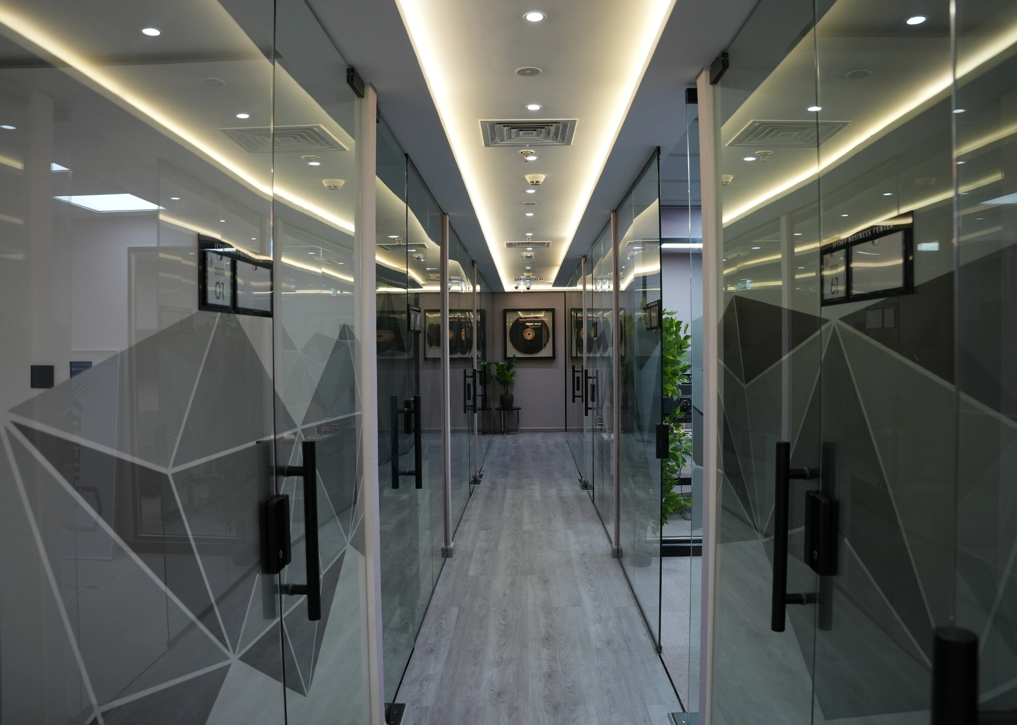Brightly lit modern office hallway with glass-walled rooms.