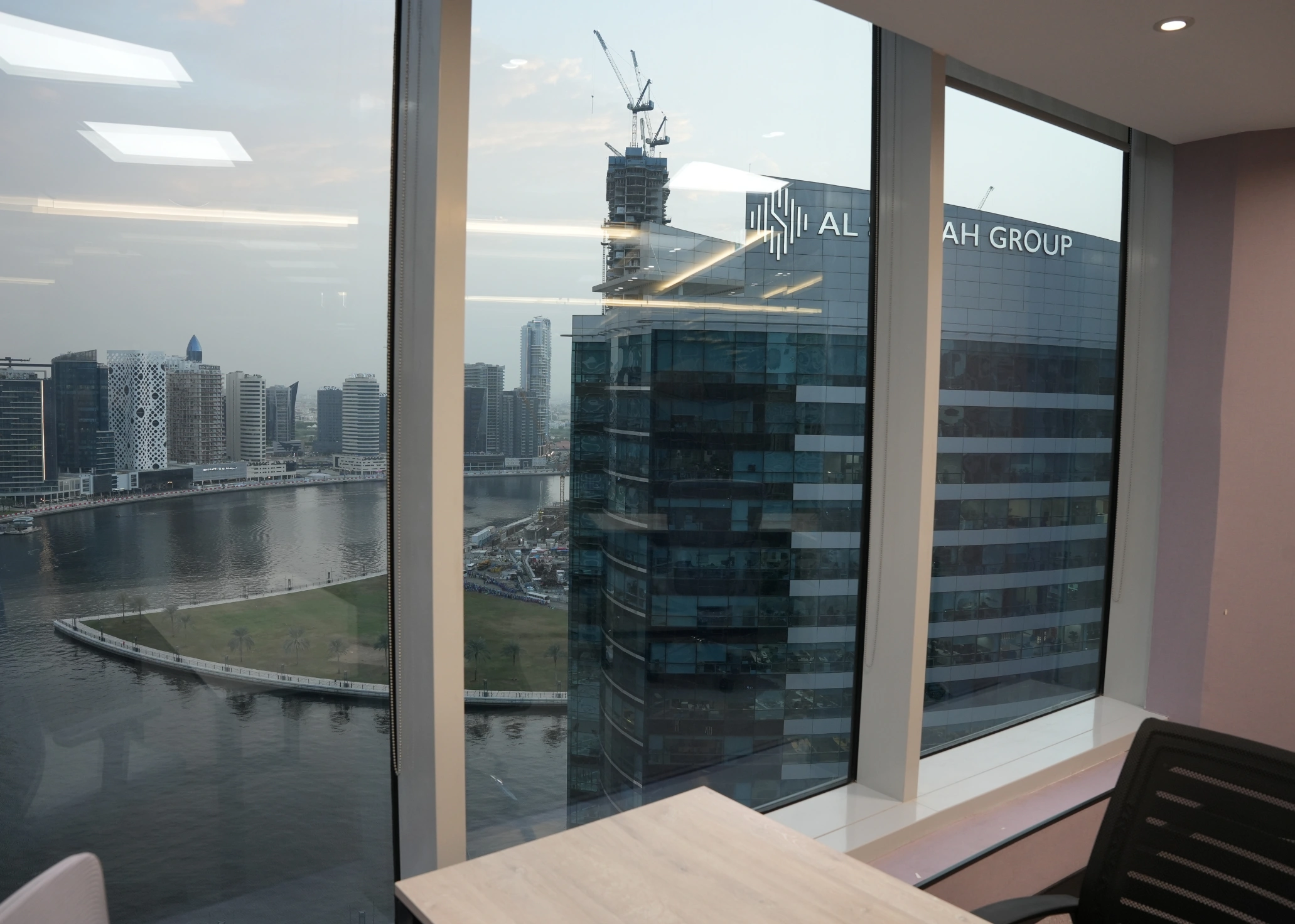 Modern office common area with a circular seating arrangement, silver peace sign sculpture, and city views.